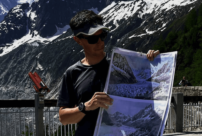 Fotografia di Ludo Ravanel con in mano immagini del ghiacciaio Mer de Glace.