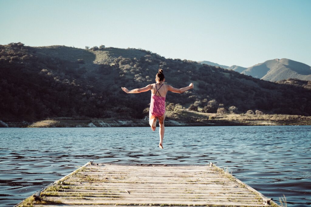 woman jumping towards water